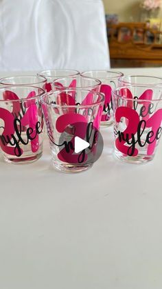 four glasses with pink and black designs sitting on top of a white tablecloth covered table