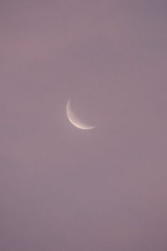 the crescent moon is seen through some clouds