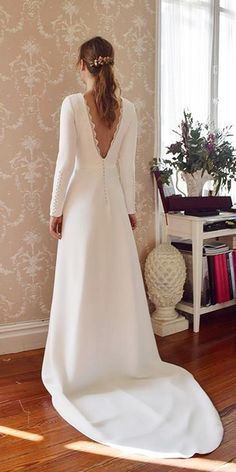 a woman in a white wedding dress standing on a wooden floor next to a window