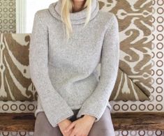 a woman sitting on top of a wooden bench wearing a gray sweater and grey pants