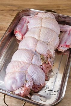 raw chicken sitting in a metal pan on a wooden table