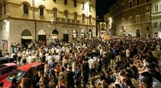 a large group of people standing in front of a building on a city street at night