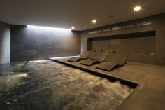 an indoor hot tub with water running down the side and lights on above it that illuminates light