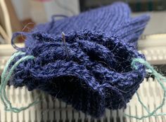 a blue knitted object sitting on top of a radiator next to yarn