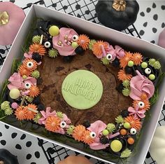 a decorated halloween cake in a box on a table with pumpkins and other decorations