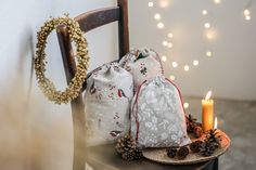 two bags sitting on top of a wooden chair next to a candle and some pine cones