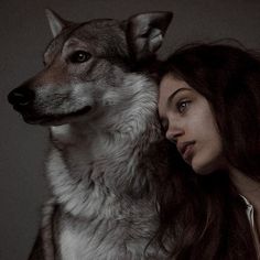 a woman standing next to a dog with her head on the back of another dog