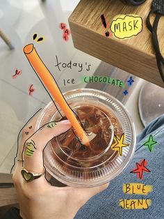 a person is holding a plastic cup with ice chocolate and an orange stick sticking out of it