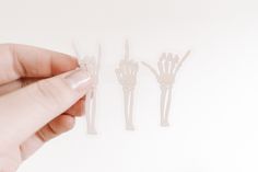 a hand holding three plastic forks in the shape of skeleton's arms and fingers