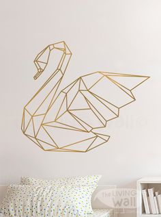 a bedroom with a white bed and a gold swan wall decal