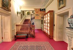 an ornate hallway with red carpet and wooden stairs leading up to the second floor area