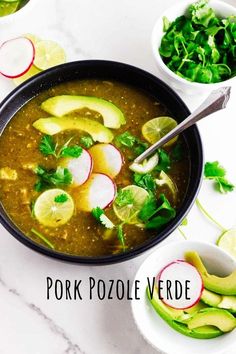 two bowls filled with soup and garnished with sliced radishes, cilantro, avocado, and lime