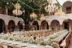 a long table is set up with white flowers and greenery for an elegant wedding reception