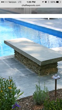 a stone bench sitting next to a swimming pool