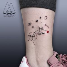 a small tattoo on the ankle of a woman's foot with stars and planets