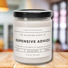 a white candle sitting on top of a wooden table next to a glass jar with the words expensive advice written in it