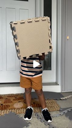 a little boy holding up a large piece of cardboard