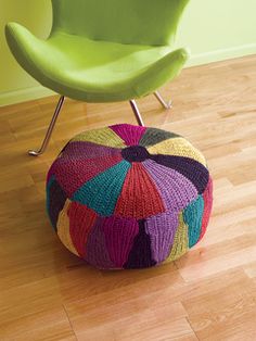 a multicolored poufle sits on the floor next to a green chair