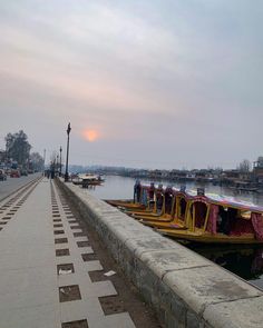 there are many boats that are docked at the water's edge in the evening