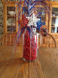 a vase filled with red, white and blue flowers on top of a wooden table