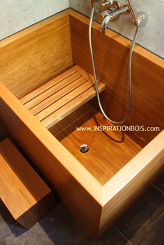 a wooden bathtub sitting on top of a tiled floor next to a shower head