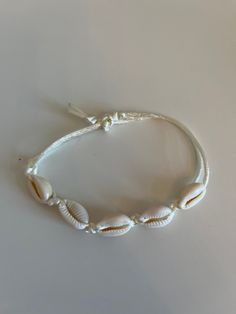 A bracelet or anklet with cowrie shells Shell Bracelet Aesthetic, Adjustable Cowrie Shell Bracelets, Adjustable Cowrie Shell Bracelet Jewelry, White Cowrie Shell Bracelet, Elegant Shell-shaped Bracelets, Beachy Adjustable Shell-shaped Bracelets, Shell Bracelet, Hair Wraps, Anklet Bracelet