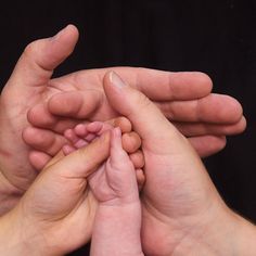 two adults and one baby are holding their hands together