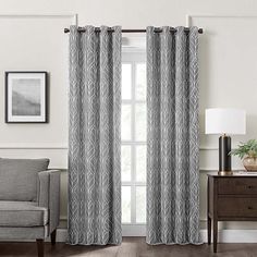 a living room with a couch, chair and window covered in gray curtain panels on the windowsill