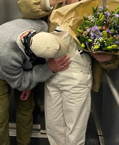 three people on an escalator with flowers in their hands and one person holding a bouquet