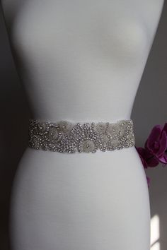 "Want to add the perfect bling to you wedding dress? This is the perfect sash to do so. This beautiful sash is made with sparkly rhinestones and beaded details, very elegant. The rhinestone trim is about 2.25\" at the widest part, with 36\" double faced ribbon at each end. You have the option to purchase this as a sash or appliqué only and at different length options. For the sash (w/ ribbon) option, the length selection you will need to make is for the rhinestone appliqué only because it will c Silver Bedazzled Bridal Belt For Wedding, Elegant Bedazzled Wedding Sash, Elegant Bedazzled Bridal Belt For Wedding, Embellished Silver Bridal Belt, Silver Embellished Bridal Belt, Silver Embellished Bridal Belt For Wedding, Embellished Fitted Sash For Party, Embellished Party Sash, Fitted Silver Crystal Bridal Belt