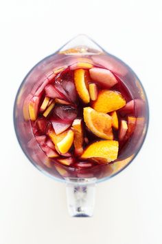 a blender filled with fruit on top of a white table