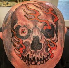 a man with a tattoo on his head has a skull and flames design on it