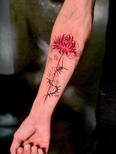 a person with a tattoo on their arm holding onto a red flower in the palm of their hand