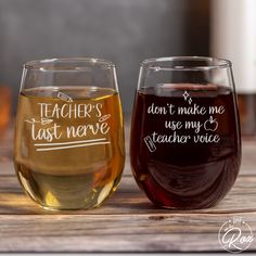 two wine glasses sitting on top of a wooden table next to each other with writing on them