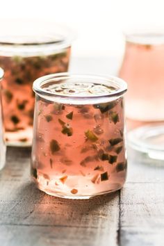 three jars filled with liquid sitting on top of a wooden table