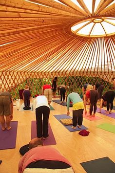 a group of people are doing yoga in a large room with wooden walls and ceiling