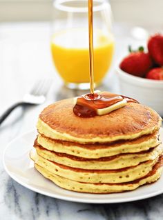 a stack of pancakes with syrup being poured on top