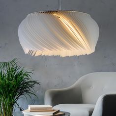 a white lamp hanging over a table next to a chair and potted palm tree