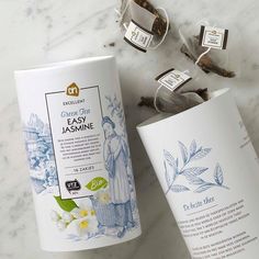 two tea bags next to each other on a marble counter top with flowers and leaves