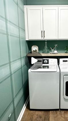 a washer and dryer in a small room with white cabinets on the wall