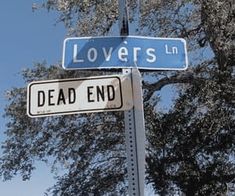 two street signs that read lovers lane and dead end on top of a pole with trees in the background