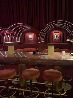 an empty bar with stools in front of it and red drapes on the wall