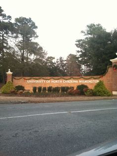 the university of north carolina sign is shown in front of a brick wall and trees