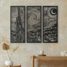 two black and white paintings hanging on the wall next to a vase with a plant in it