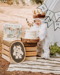 a baby is dressed up as a bear with a crown on his head and holding a cake