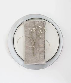 a white plate topped with a napkin covered in baby's breath flowers and twine