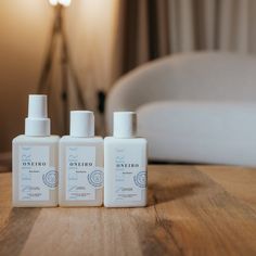 three bottles of hand sanitizers sitting on a table in front of a bed