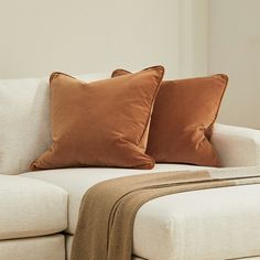 two brown pillows sitting on top of a white couch