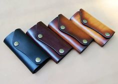 three leather wallets sitting on top of a white table next to each other with holes in them