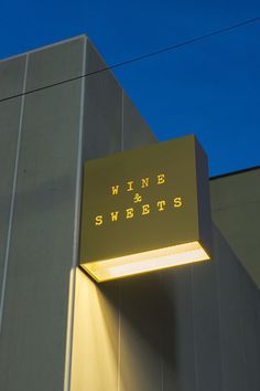 an illuminated sign on the side of a building that says wind and sweets below it